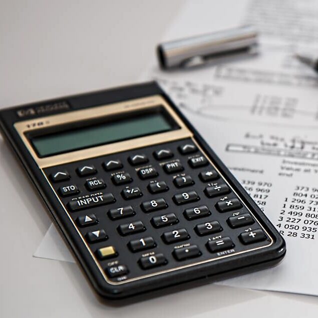 Calculator, pen, and accounting paperwork