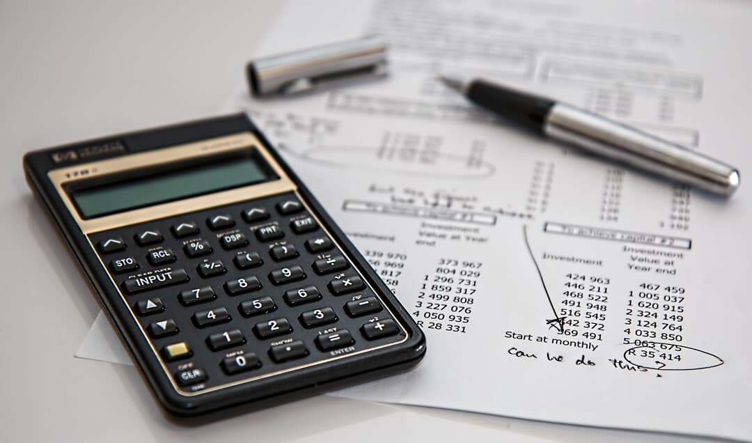 Calculator, pen, and accounting paperwork